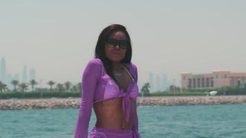 Young swarthy woman in a white bikini and a light dress on board a private boat against the backdrop of the city video