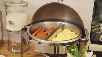 A breakfast table is set in a small hotel. Sausages, yogurt, salads, sauces, drinks video