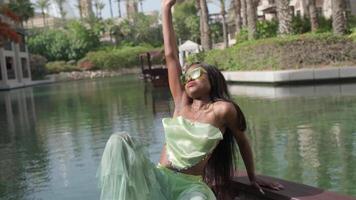 Relaxed interracial woman in a dress sits on the bow of a boat passing through a canal in Dubai video