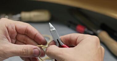 Jeweler collects jewelry with tweezers on the table video