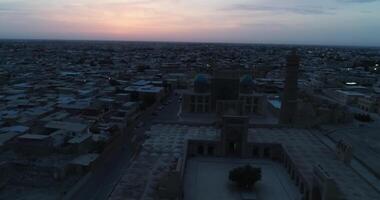 A drone flies over the architectural complex Poi-Kalon among old houses in Bukhara, Uzbekistan. Early cloudy morning video