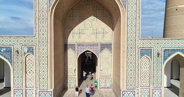 The drone flies near the main gate of the ancient complex Lyab-i Hauz. Groups of tourists near the gate. Old Bukhara, Uzbekistan. video