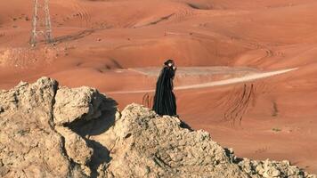 A man with a staff in his hand and the clothes of a shaman stands on a rock among the sands of the desert and dances video