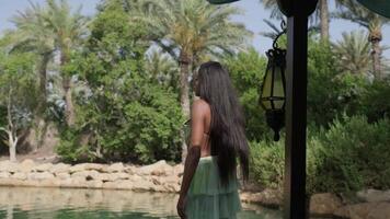 Relaxed interracial woman in a dress stands at the bow of a boat passing through a canal in Dubai video