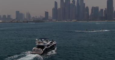 A drone flies by a private boat sailing on a calm sea towards the city video