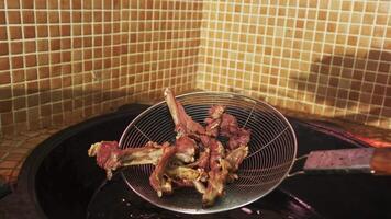 The chef takes pieces of meat out of the oil boiling in a cauldron with a slotted spoon video