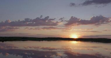 Sunrise on cloudy morning over calm lake in calm weather video