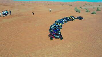 un zumbido moscas terminado un caravana de buggies en pie en un Desierto arena duna. video