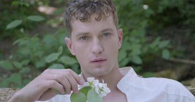 Man with a flower in his hand sits among a garden video