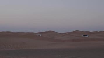 A caravan of white off-road vehicles rides through the sand dunes of the desert video