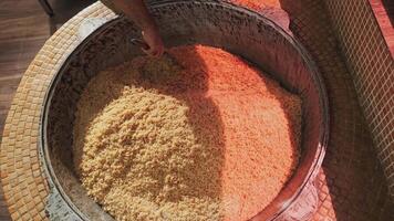 The chef stirs steaming rice in a large pilaf cauldron with a slotted spoon video