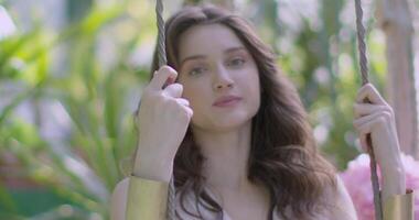 Young woman in a light white dress swings on swing video