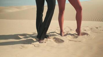 Two girls pose standing barefoot on the sand video