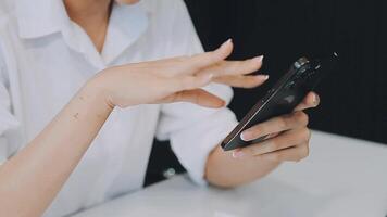 silhueta de tiro recortado de um jovem trabalhando em casa usando telefone inteligente e notebook, mãos do homem usando telefone inteligente no interior, homem em seu local de trabalho usando tecnologia, sinalizador de luz video