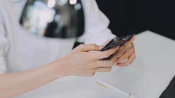 silhueta de tiro recortado de um jovem trabalhando em casa usando telefone inteligente e notebook, mãos do homem usando telefone inteligente no interior, homem em seu local de trabalho usando tecnologia, sinalizador de luz video