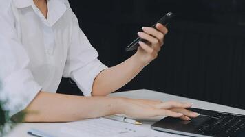 Silhouette of cropped shot of a young man working from home using smart phone and notebook computer, man's hands using smart phone in interior, man at his workplace using technology, flare light video