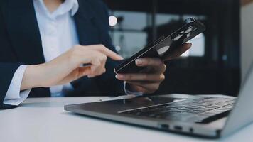 Silhouette of cropped shot of a young man working from home using smart phone and notebook computer, man's hands using smart phone in interior, man at his workplace using technology, flare light video