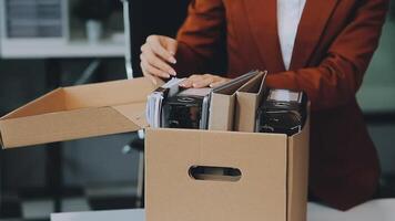 Upset female employee packing belongings in box, frustrated stressed girl getting fired from job ready to leave on last day at work. sad office worker desperate from work video