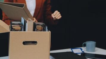 Upset female employee packing belongings in box, frustrated stressed girl getting fired from job ready to leave on last day at work. sad office worker desperate from work video