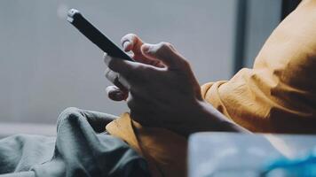 Silhouette of cropped shot of a young man working from home using smart phone and notebook computer, man's hands using smart phone in interior, man at his workplace using technology, flare light video