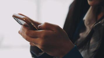 Silhouette of cropped shot of a young man working from home using smart phone and notebook computer, man's hands using smart phone in interior, man at his workplace using technology, flare light video