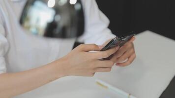 silhouette di ritagliata tiro di un' giovane uomo Lavorando a partire dal casa utilizzando inteligente Telefono e taccuino computer, dell'uomo mani utilizzando inteligente Telefono nel interno, uomo a il suo posto di lavoro utilizzando tecnologia, bagliore leggero video