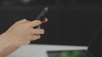 silhouette di ritagliata tiro di un' giovane uomo Lavorando a partire dal casa utilizzando inteligente Telefono e taccuino computer, dell'uomo mani utilizzando inteligente Telefono nel interno, uomo a il suo posto di lavoro utilizzando tecnologia, bagliore leggero video