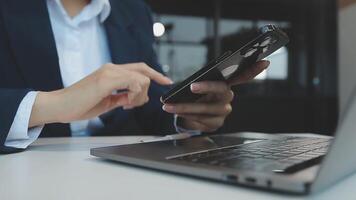 silhouette di ritagliata tiro di un' giovane uomo Lavorando a partire dal casa utilizzando inteligente Telefono e taccuino computer, dell'uomo mani utilizzando inteligente Telefono nel interno, uomo a il suo posto di lavoro utilizzando tecnologia, bagliore leggero video