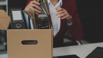 Upset female employee packing belongings in box, frustrated stressed girl getting fired from job ready to leave on last day at work. sad office worker desperate from work video