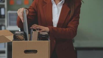 Upset female employee packing belongings in box, frustrated stressed girl getting fired from job ready to leave on last day at work. sad office worker desperate from work video