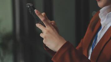 Silhouette of cropped shot of a young man working from home using smart phone and notebook computer, man's hands using smart phone in interior, man at his workplace using technology, flare light video