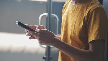 silhouette d'une photo recadrée d'un jeune homme travaillant à domicile à l'aide d'un smartphone et d'un ordinateur portable, les mains de l'homme utilisant un smartphone à l'intérieur, un homme sur son lieu de travail utilisant la technologie, une lumière parasite video