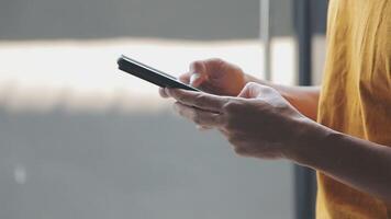 silhouette di ritagliata tiro di un' giovane uomo Lavorando a partire dal casa utilizzando inteligente Telefono e taccuino computer, dell'uomo mani utilizzando inteligente Telefono nel interno, uomo a il suo posto di lavoro utilizzando tecnologia, bagliore leggero video