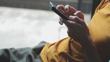 silhouette di ritagliata tiro di un' giovane uomo Lavorando a partire dal casa utilizzando inteligente Telefono e taccuino computer, dell'uomo mani utilizzando inteligente Telefono nel interno, uomo a il suo posto di lavoro utilizzando tecnologia, bagliore leggero video