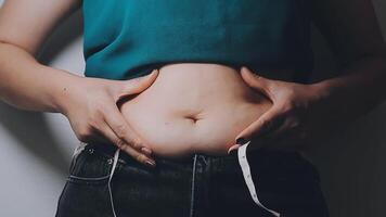 mujer cuerpo grasa barriga. obeso mujer mano participación excesivo barriga gordo. dieta estilo de vida concepto a reducir barriga y forma arriba sano estómago músculo. video