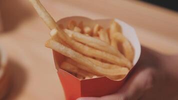 Closeup image of a woman holding and eating french fries and hamburger with fried chicken on the table at home video