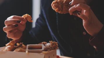 dichtbij omhoog focus vrouw hand- houden gebakken kip voor eet, meisje met snel voedsel concept video