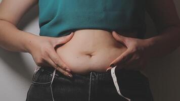 mujer cuerpo grasa barriga. obeso mujer mano participación excesivo barriga gordo. dieta estilo de vida concepto a reducir barriga y forma arriba sano estómago músculo. video