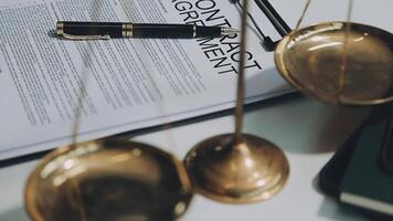 Business and lawyers discussing contract papers with brass scale on desk in office. Law, legal services, advice, justice and law concept picture with film grain effect video