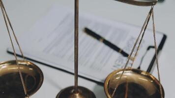 Business and lawyers discussing contract papers with brass scale on desk in office. Law, legal services, advice, justice and law concept picture with film grain effect video