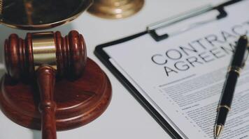 Business and lawyers discussing contract papers with brass scale on desk in office. Law, legal services, advice, justice and law concept picture with film grain effect video