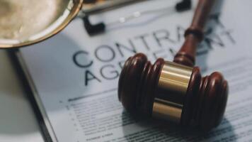 Business and lawyers discussing contract papers with brass scale on desk in office. Law, legal services, advice, justice and law concept picture with film grain effect video