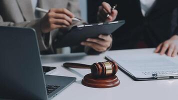 Business and lawyers discussing contract papers with brass scale on desk in office. Law, legal services, advice, justice and law concept picture with film grain effect video