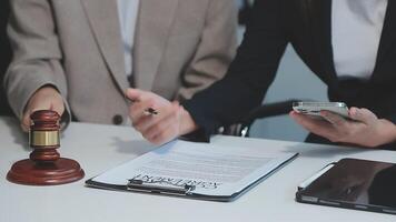 Business and lawyers discussing contract papers with brass scale on desk in office. Law, legal services, advice, justice and law concept picture with film grain effect video