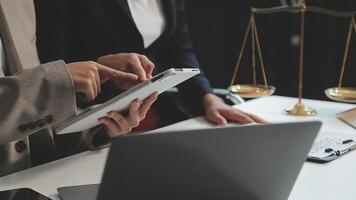 Business and lawyers discussing contract papers with brass scale on desk in office. Law, legal services, advice, justice and law concept picture with film grain effect video