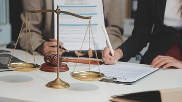 Business and lawyers discussing contract papers with brass scale on desk in office. Law, legal services, advice, justice and law concept picture with film grain effect video