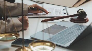 Business and lawyers discussing contract papers with brass scale on desk in office. Law, legal services, advice, justice and law concept picture with film grain effect video