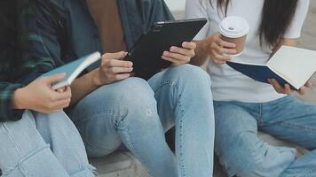 Group of happy young Asian college students sitting on a bench, looking at a laptop screen, discussing and brainstorming on their school project together. video