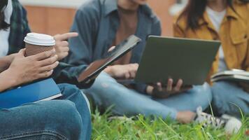 Group of happy young Asian college students sitting on a bench, looking at a laptop screen, discussing and brainstorming on their school project together. video