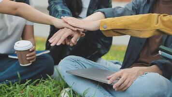 Group of happy young Asian college students sitting on a bench, looking at a laptop screen, discussing and brainstorming on their school project together. video